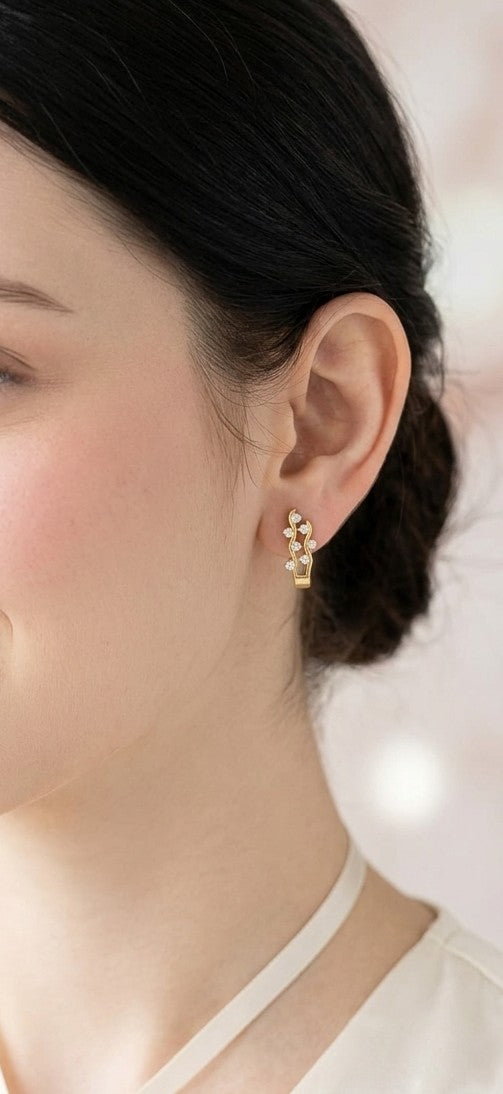 18K yellow gold diamond wave hoop earrings featuring flowing open gold curves with scattered round brilliant diamonds.