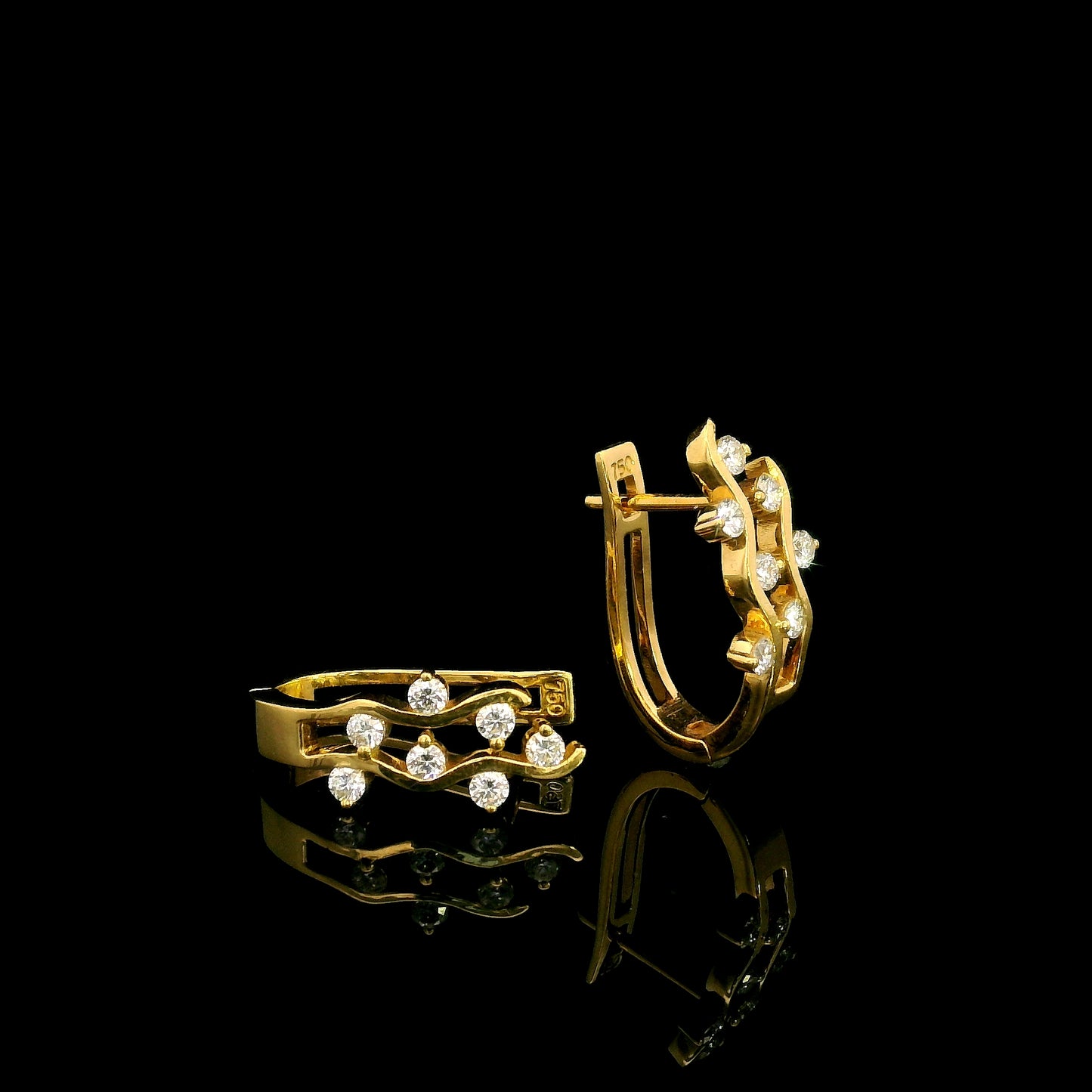 18K yellow gold diamond wave hoop earrings featuring flowing open gold curves with scattered round brilliant diamonds.