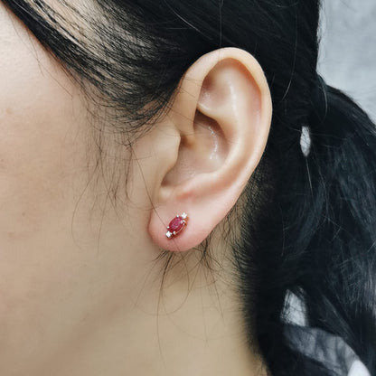 Close-up of an ear wearing a red gemstone earring with a blurred background