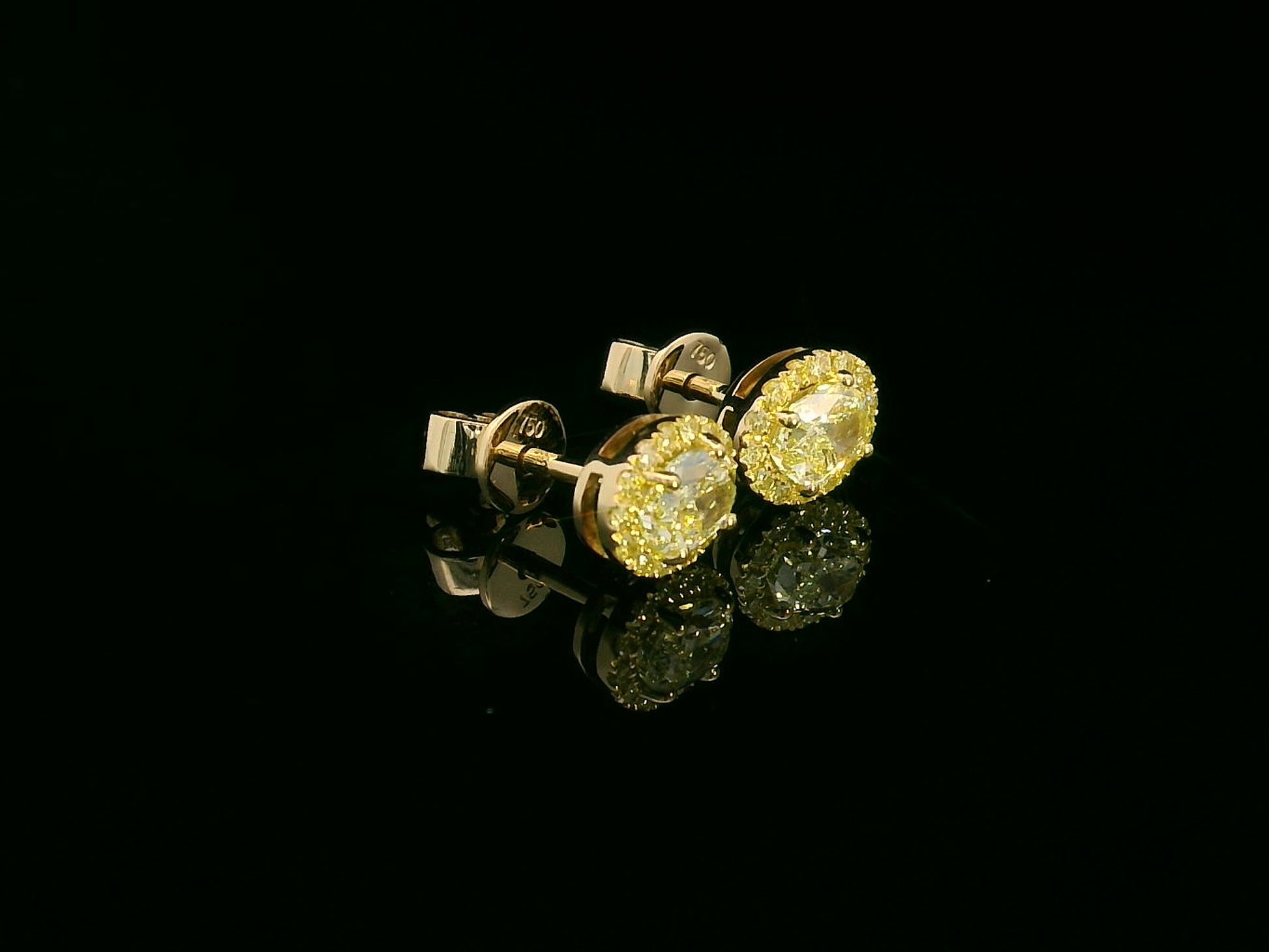 Side view of yellow gold earrings with sparkling fancy yellow diamonds
