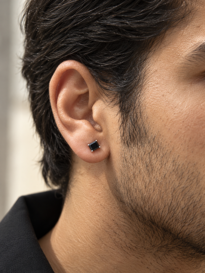 Square black diamond stud earring for men featuring a 0.50 carat black diamond in a four-prong 18K white gold setting, sold individually.