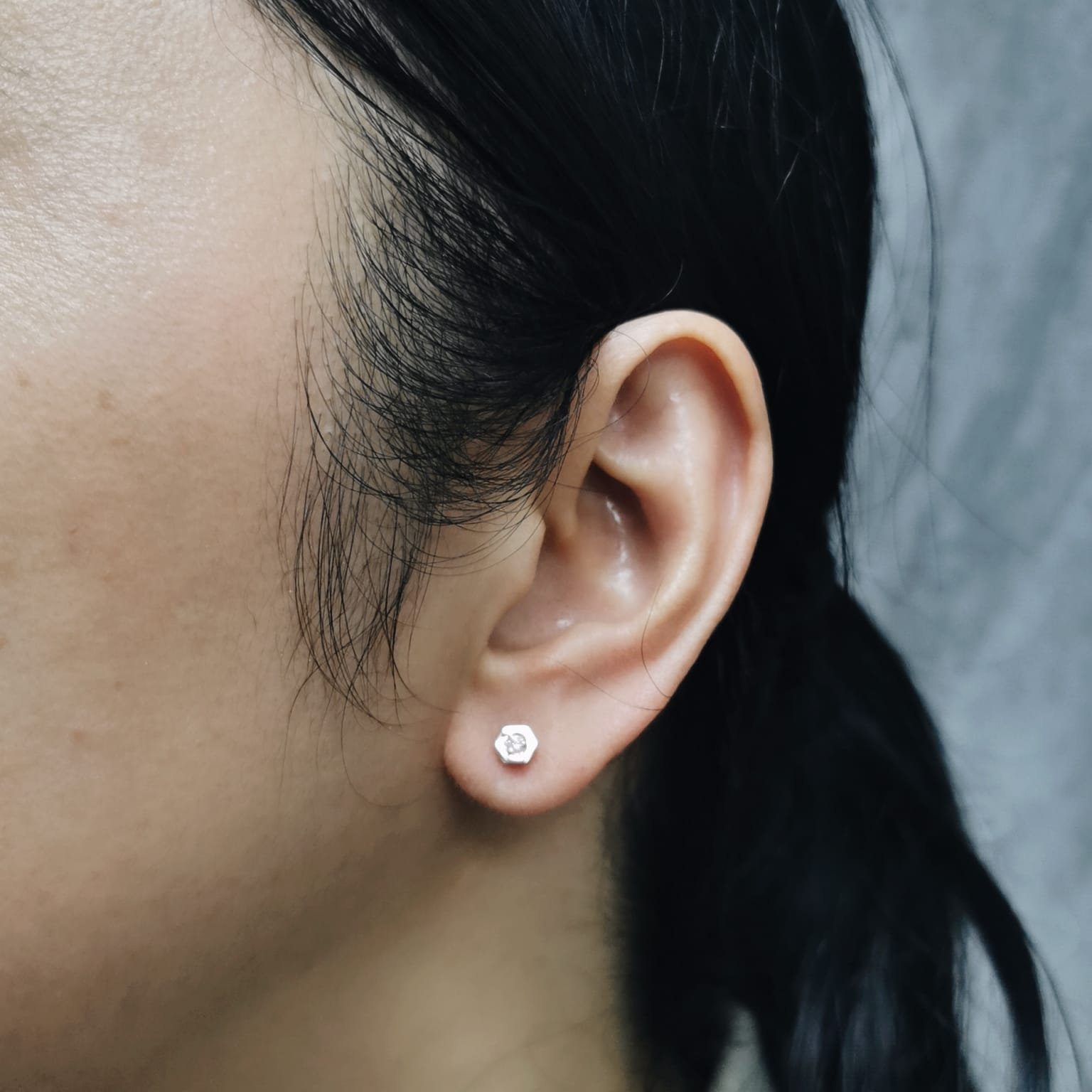 18k rose gold hexagon diamond stud earrings worn on ear for scale and fit