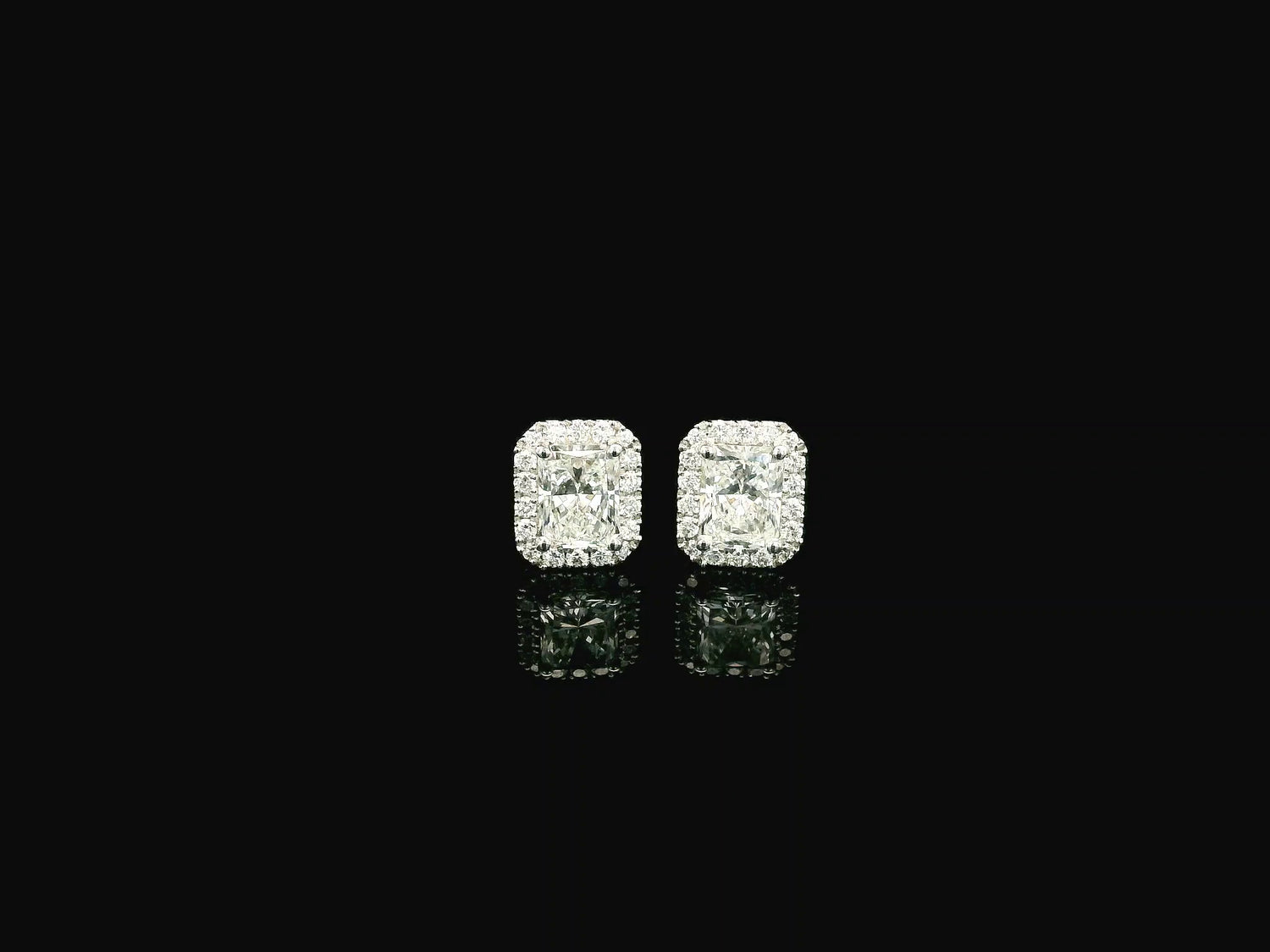 18K white gold diamond halo stud earrings featuring two GIA certified radiant cut diamonds totaling 1.40 carats surrounded by 0.27 carat natural diamond halos.
