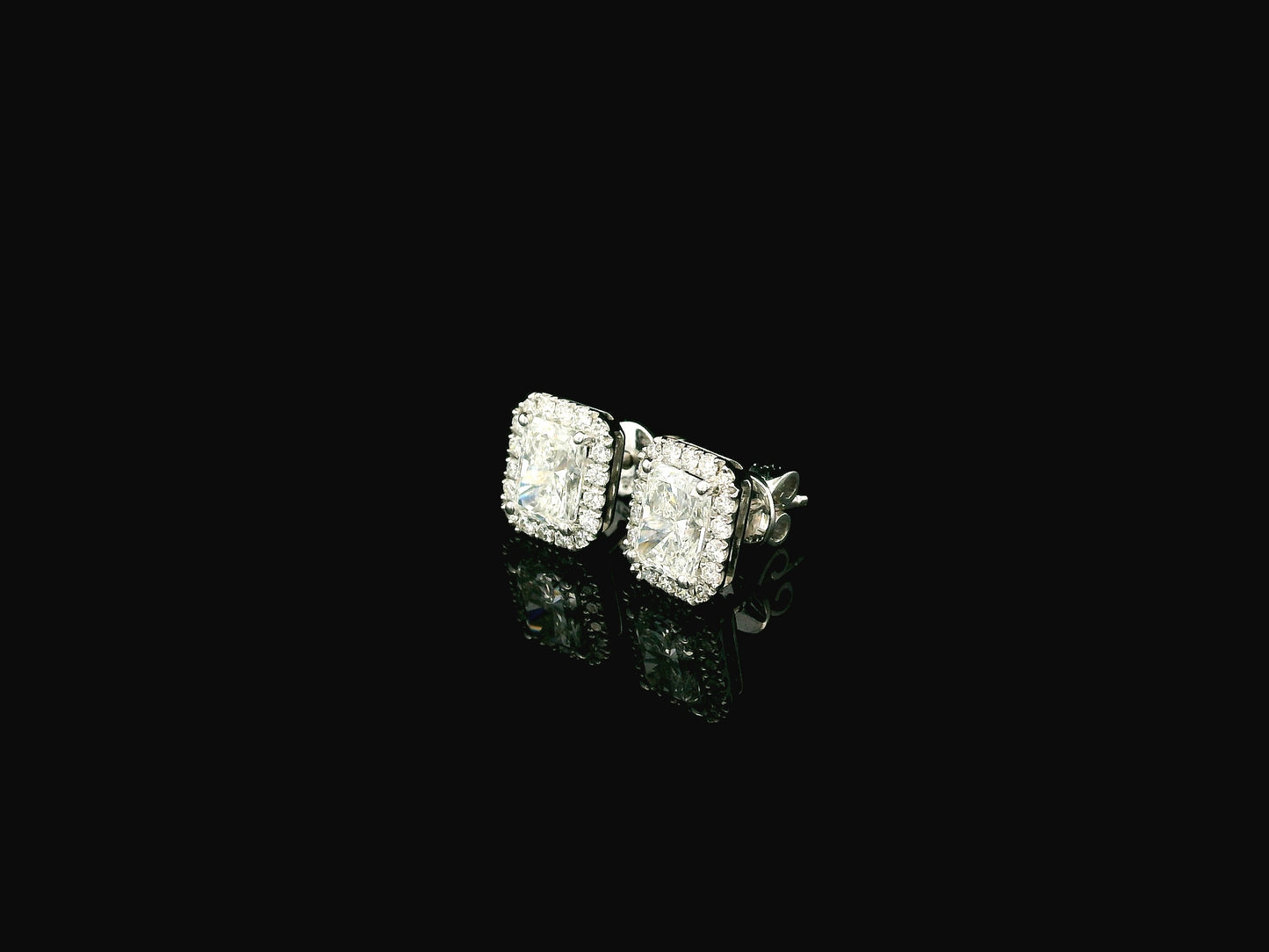 18K white gold diamond halo stud earrings featuring two GIA certified radiant cut diamonds totaling 1.40 carats surrounded by 0.27 carat natural diamond halos.