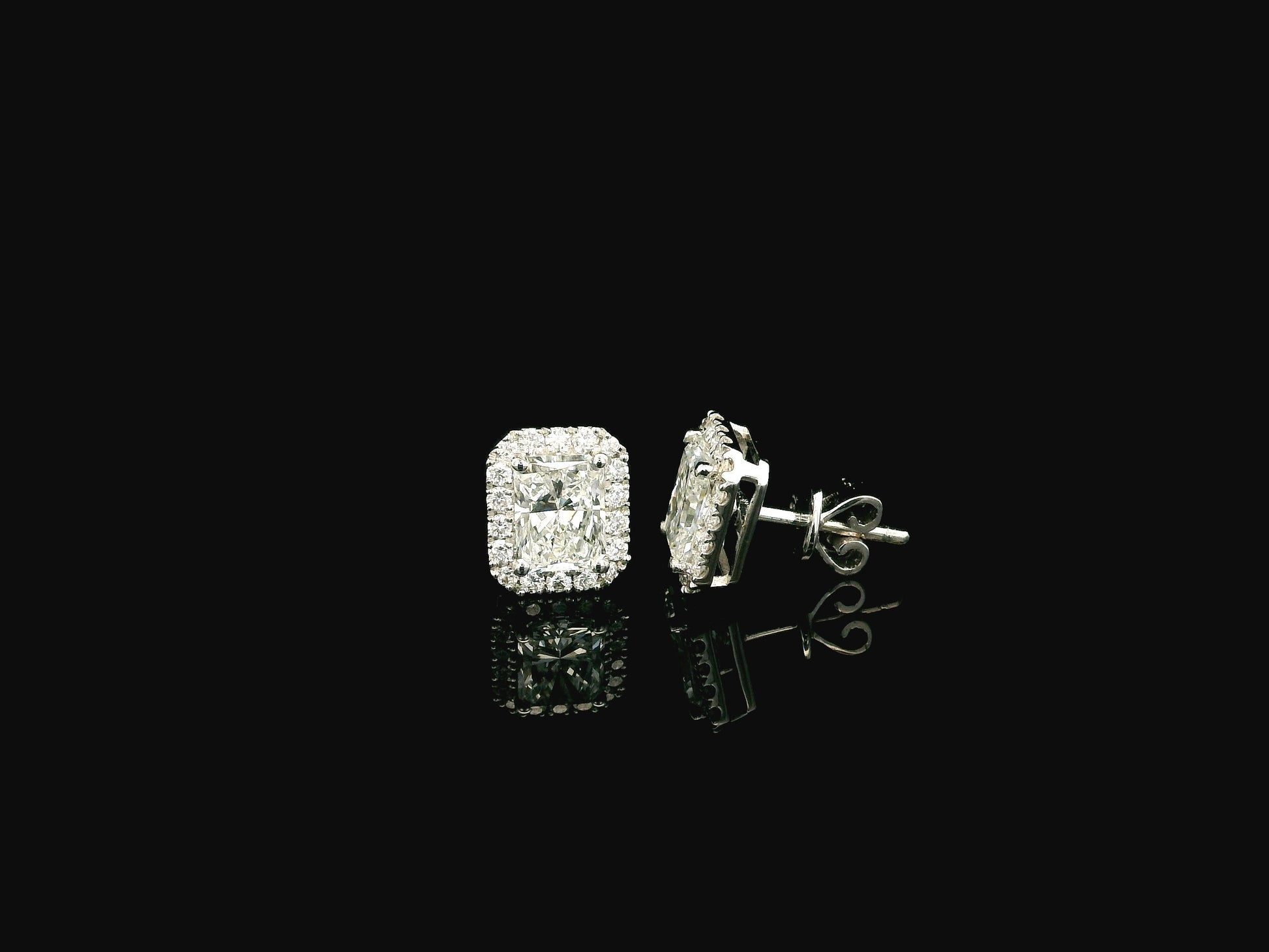 18K white gold diamond halo stud earrings featuring two GIA certified radiant cut diamonds totaling 1.40 carats surrounded by 0.27 carat natural diamond halos.
