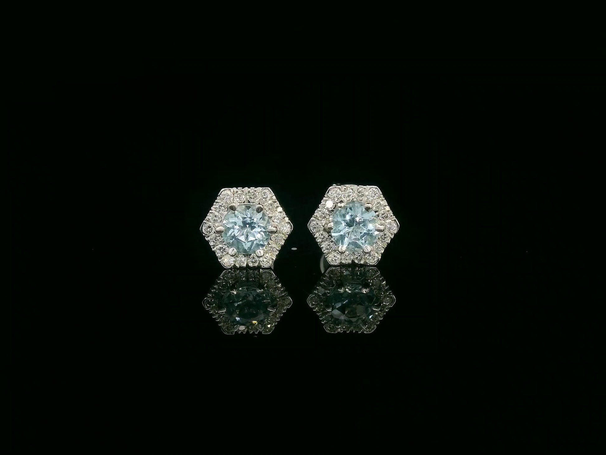 Front view of 18k gold stud earrings with round aquamarines and diamond halo