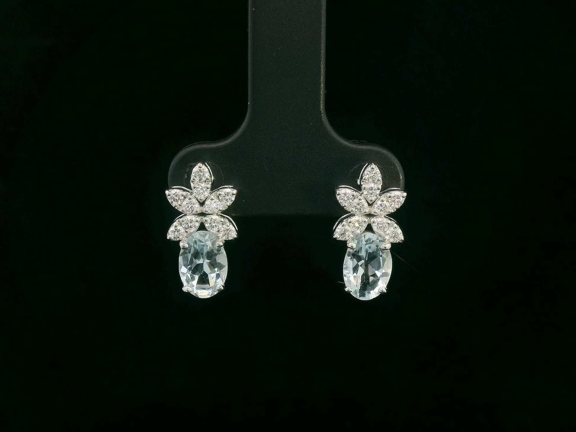 Front view of 18k gold drop earrings with oval aquamarines and floral diamond cluster