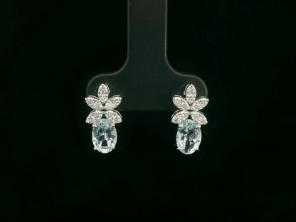 Front view of 18k gold drop earrings with oval aquamarines and floral diamond cluster