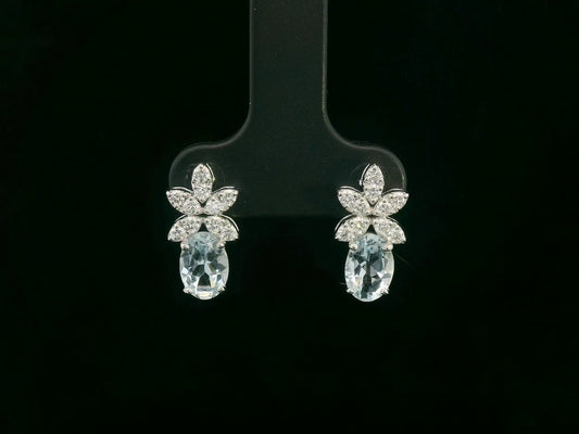 Front view of 18k gold drop earrings with oval aquamarines and floral diamond cluster