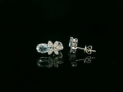 Front view of 18k gold drop earrings with oval aquamarines and floral diamond cluster