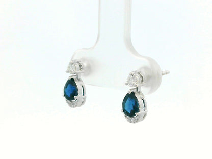 18K white gold drop earrings featuring 0.90ct pear-cut blue sapphires suspended beneath round brilliant diamonds with 0.15ct pavé diamond accent arc.