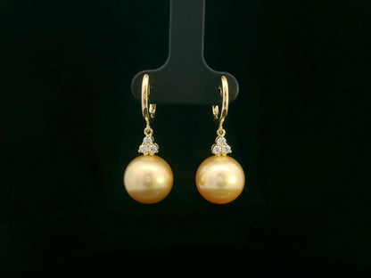 18k yellow gold South Sea pearl earrings featuring golden pearls suspended from hoops with diamond pyramid clusters above each pearl.