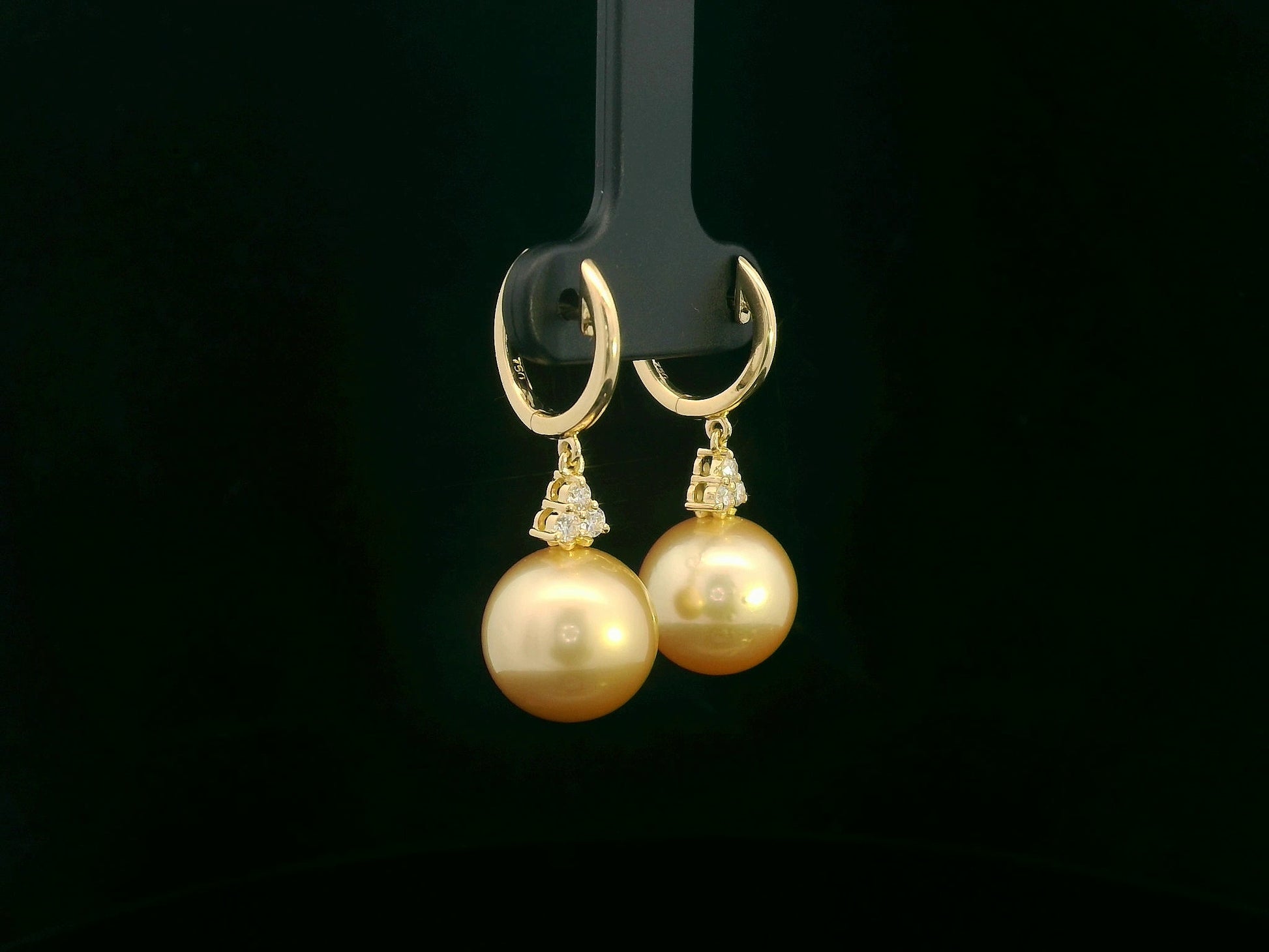 18k yellow gold South Sea pearl earrings featuring golden pearls suspended from hoops with diamond pyramid clusters above each pearl.