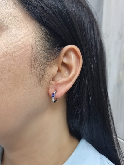 18K white gold hoop earrings featuring 0.44ct oval-cut tanzanites with 0.19ct pavé diamonds along the front curve of each hoop.