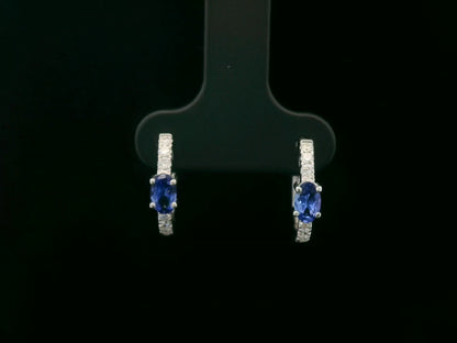 18K white gold hoop earrings featuring 0.44ct oval-cut tanzanites with 0.19ct pavé diamonds along the front curve of each hoop.