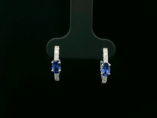 18K white gold hoop earrings featuring 0.44ct oval-cut tanzanites with 0.19ct pavé diamonds along the front curve of each hoop.