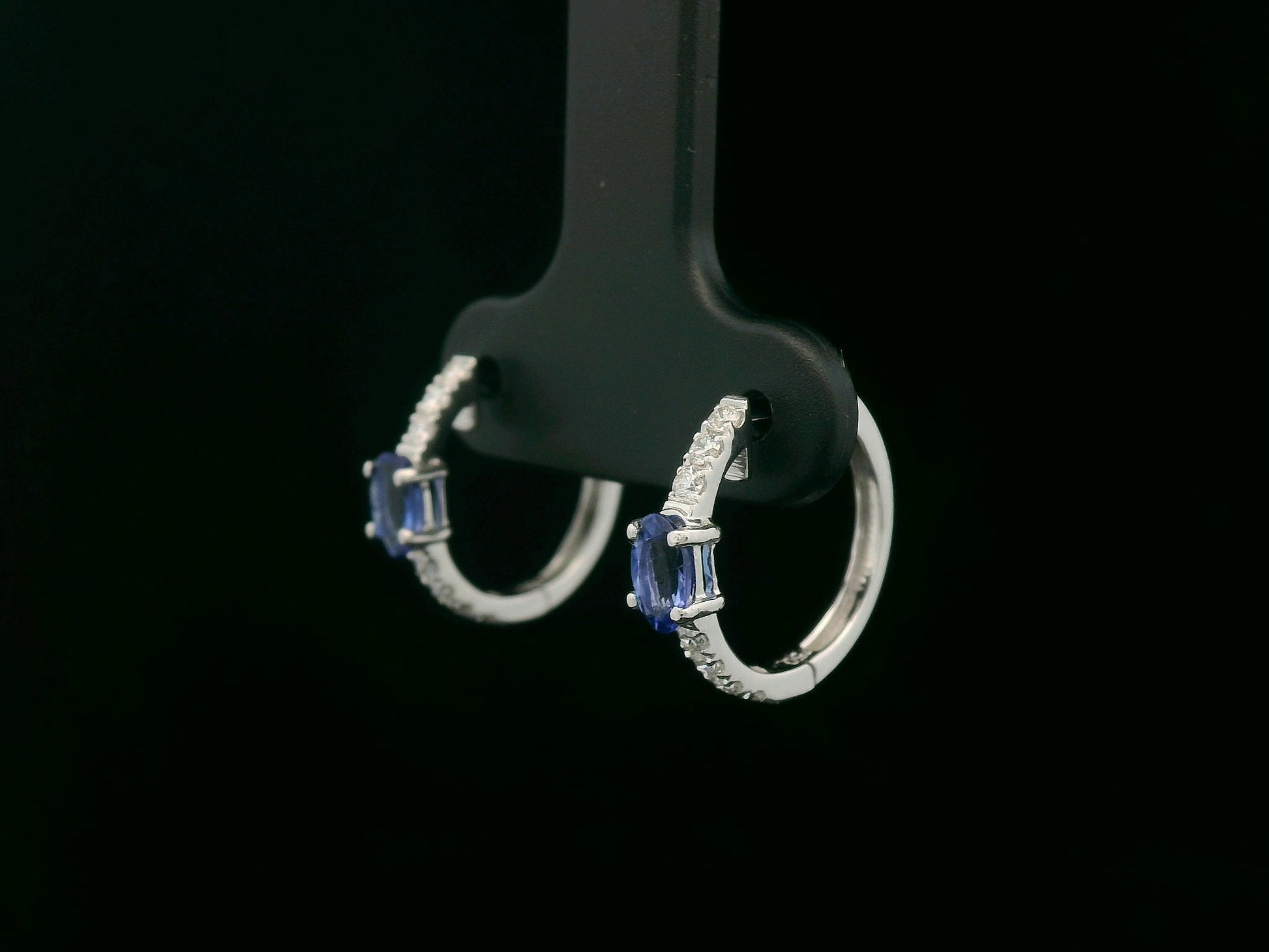 18K white gold hoop earrings featuring 0.44ct oval-cut tanzanites with 0.19ct pavé diamonds along the front curve of each hoop.