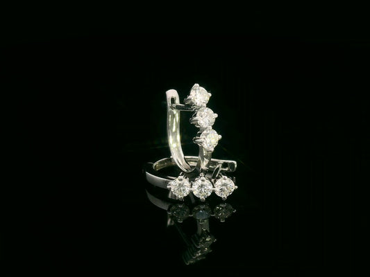 18K white gold huggie hoop earrings featuring three round brilliant-cut diamonds along the front, totaling 0.57 carat.