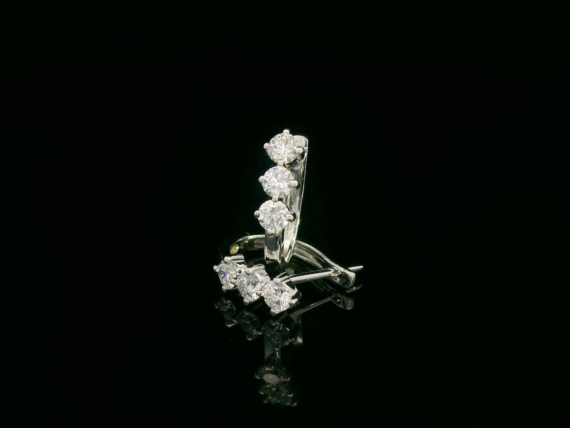 18K white gold huggie hoop earrings featuring three round brilliant-cut diamonds along the front, totaling 0.57 carat.