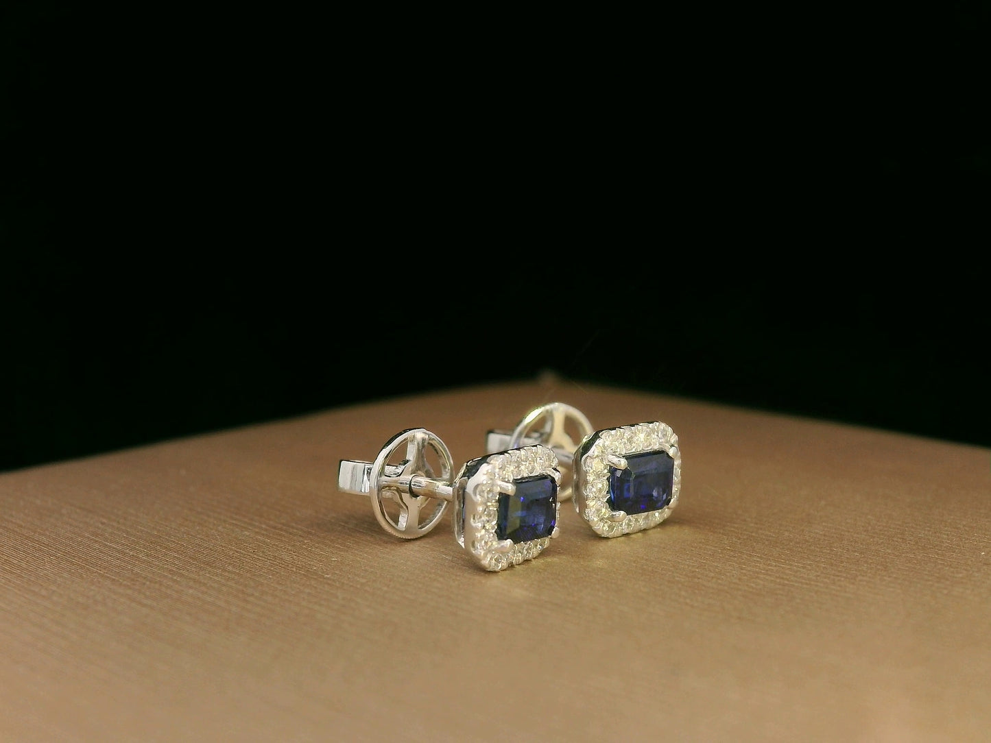 Minimalist 18K white gold halo stud earrings with emerald-cut blue sapphires and diamond accents 