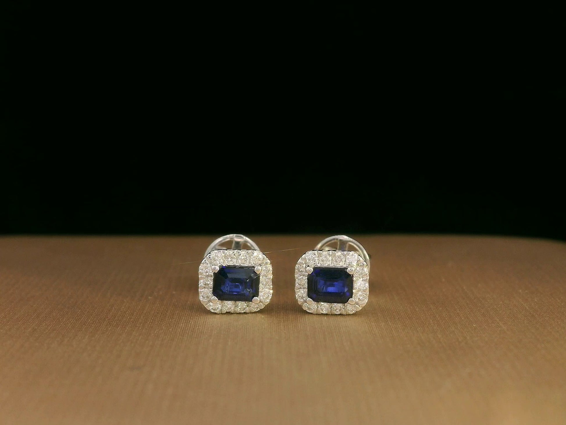 Minimalist 18K white gold halo stud earrings with emerald-cut blue sapphires and diamond accents 
