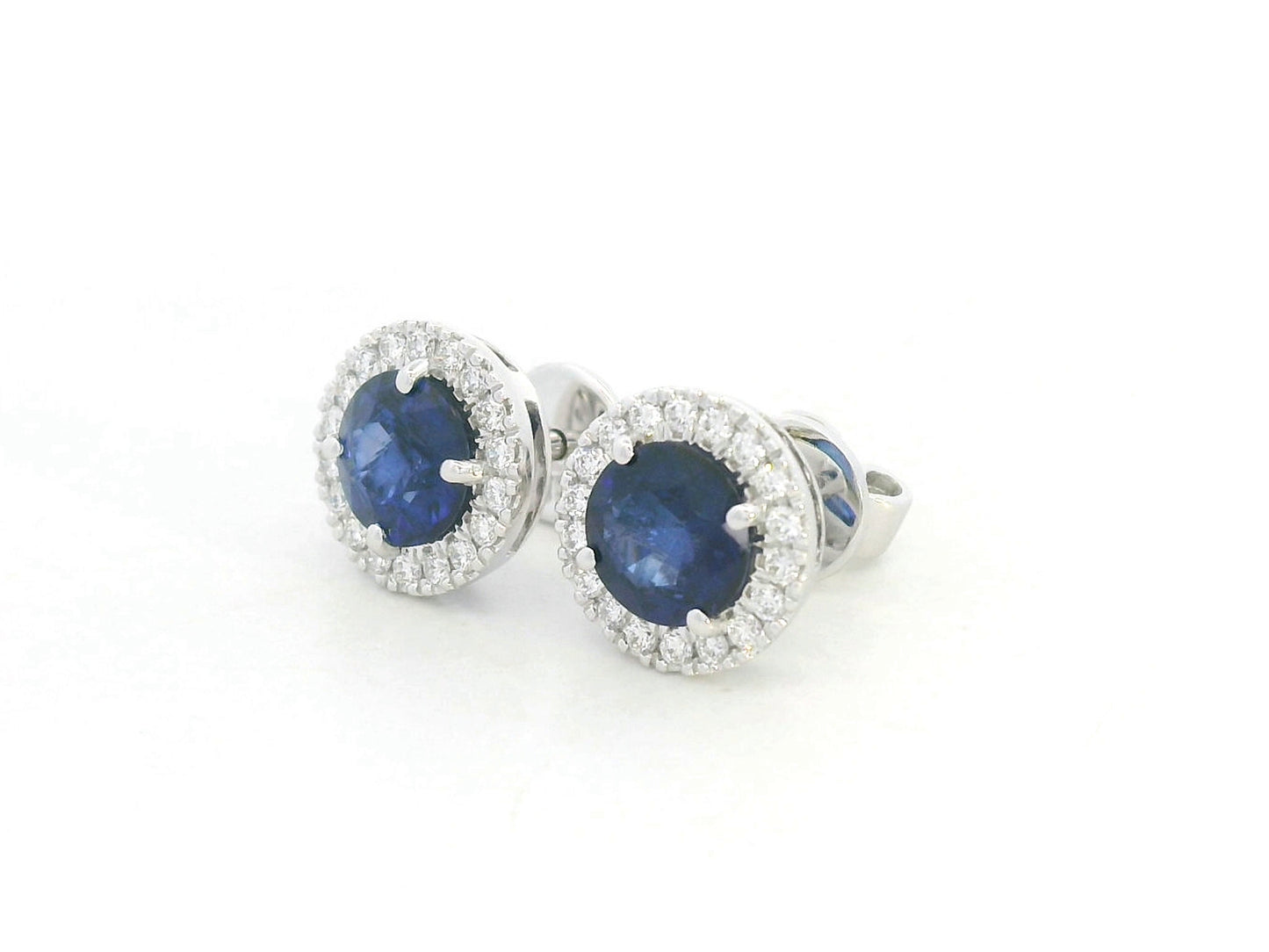 18K white gold blue sapphire and diamond halo stud earrings with round sapphires, 1.40 carat sapphires and 0.20 carat diamonds by Emirates Diamonds