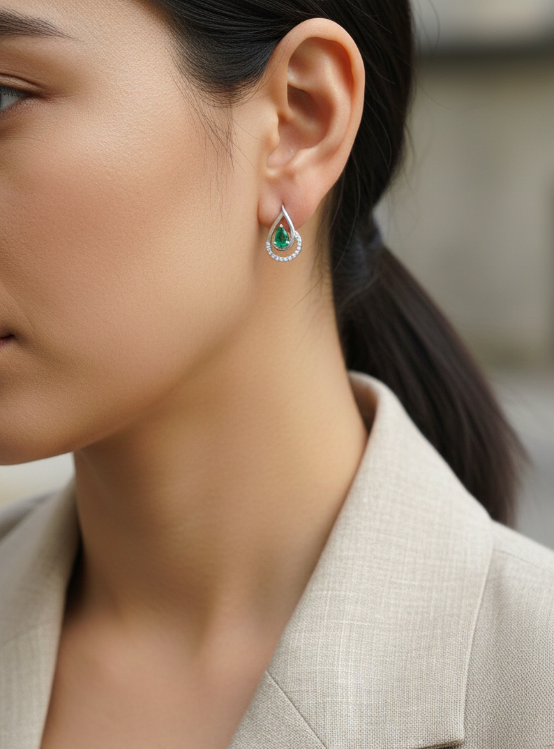 Emerald and diamond stud earrings in 18K white gold with pear-cut emeralds and pavé diamond accents by Emirates Diamonds