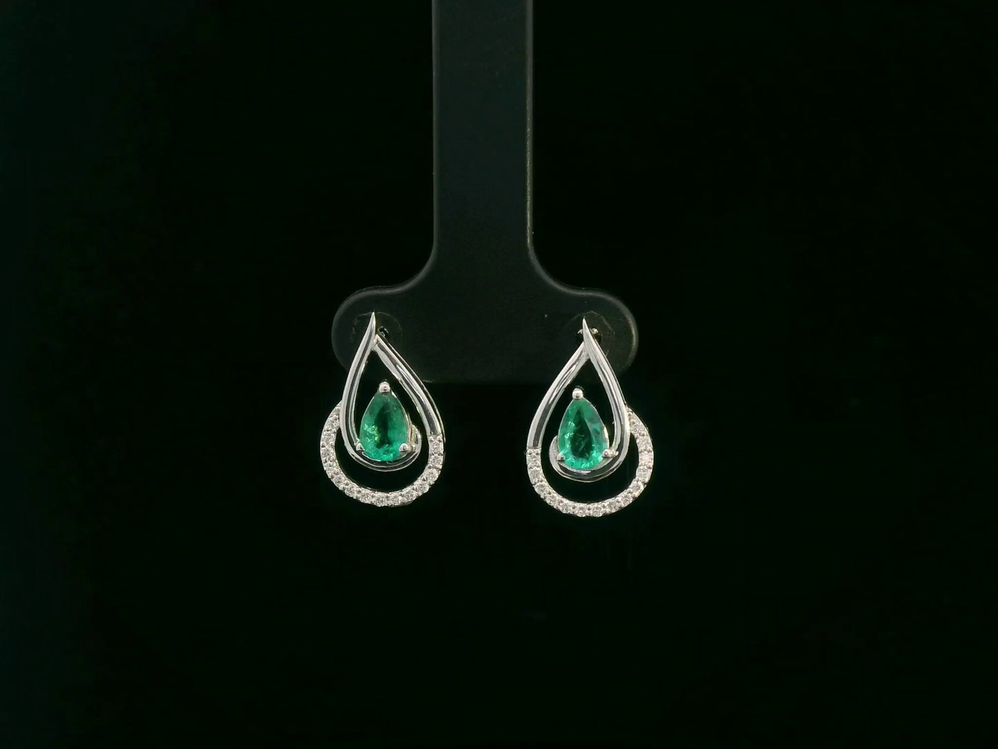 Emerald and diamond stud earrings in 18K white gold with pear-cut emeralds and pavé diamond accents by Emirates Diamonds