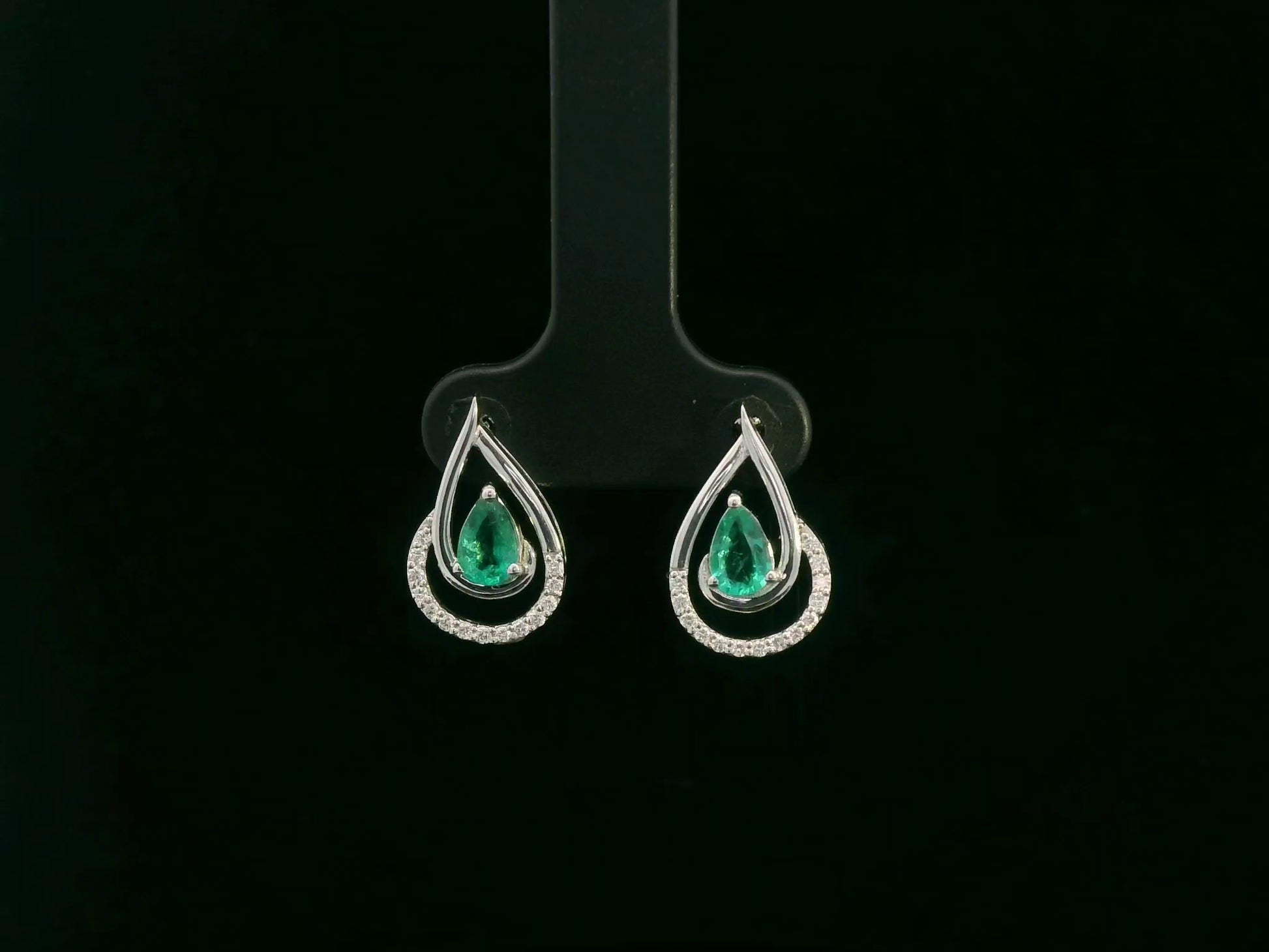 Emerald and diamond stud earrings in 18K white gold with pear-cut emeralds and pavé diamond accents by Emirates Diamonds