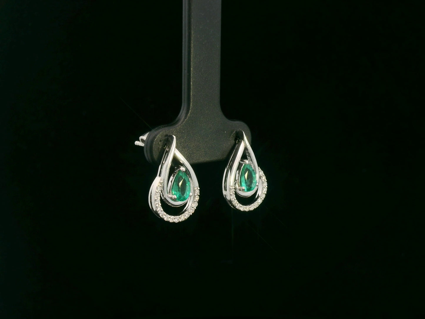 Emerald and diamond stud earrings in 18K white gold with pear-cut emeralds and pavé diamond accents by Emirates Diamonds