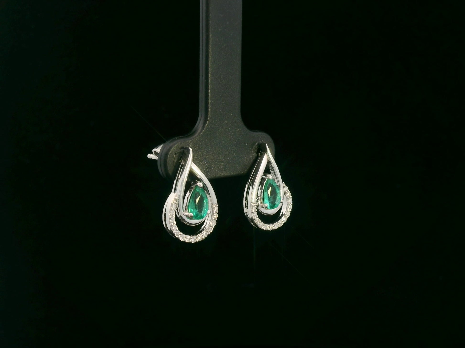 Emerald and diamond stud earrings in 18K white gold with pear-cut emeralds and pavé diamond accents by Emirates Diamonds