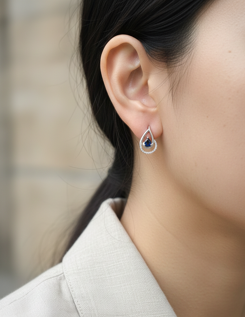 Blue sapphire and diamond stud earrings in 18K white gold with pear-cut sapphires and pavé diamond accents by Emirates Diamonds