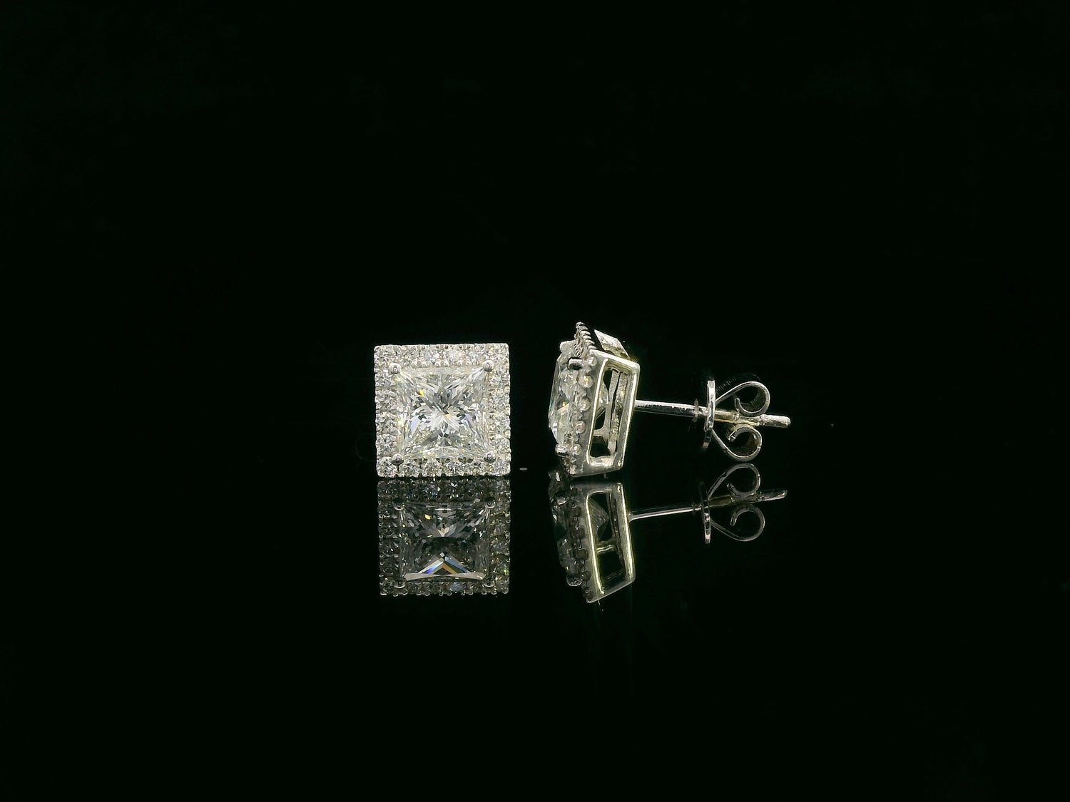 Princess cut diamond halo stud earrings in 18K white gold featuring GIA certified 1.01 carat E color VS2 diamonds with halo accents by Emirates Diamonds