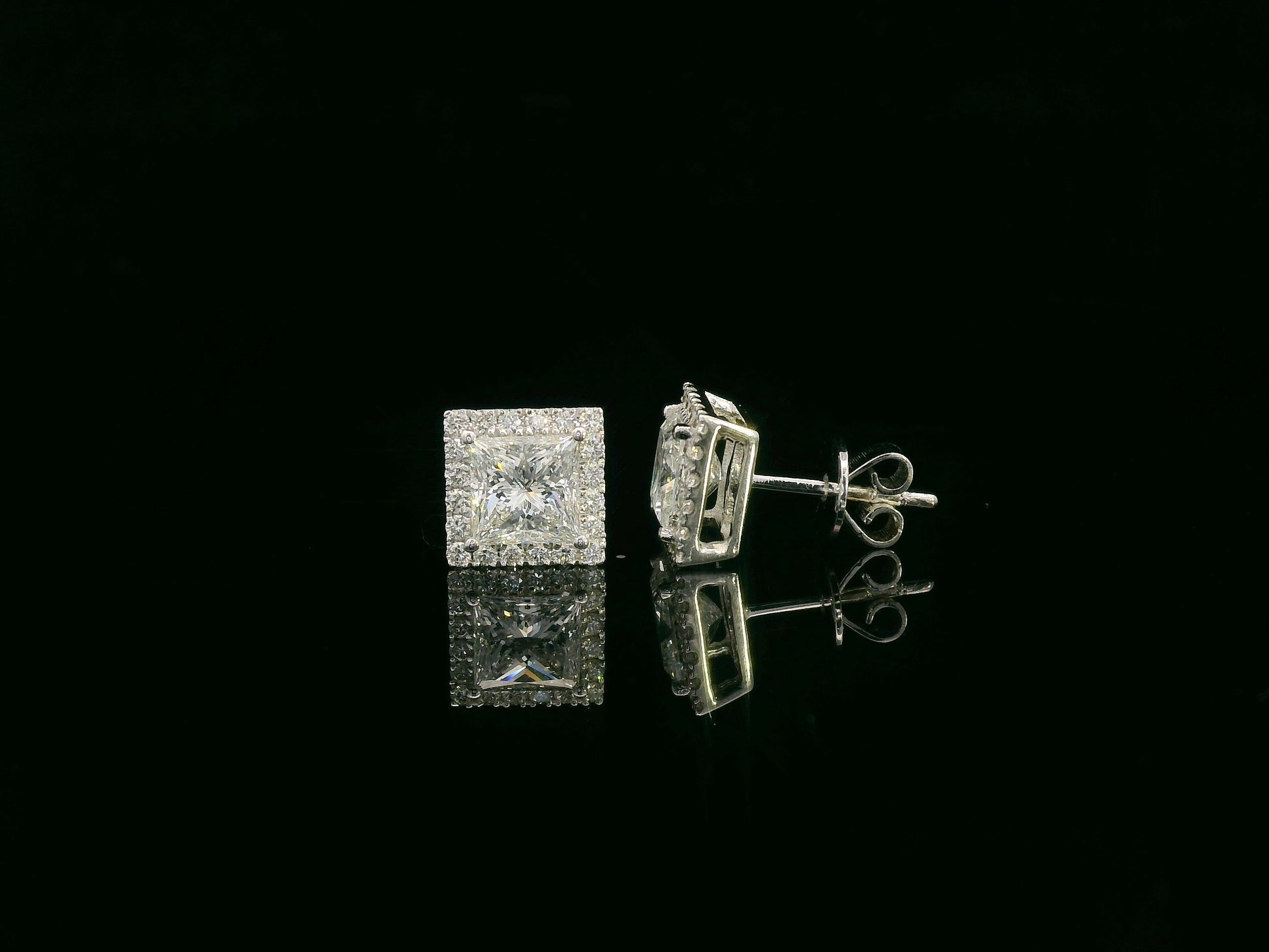 Princess cut diamond halo stud earrings in 18K white gold featuring GIA certified 1.01 carat E color VS2 diamonds with halo accents by Emirates Diamonds