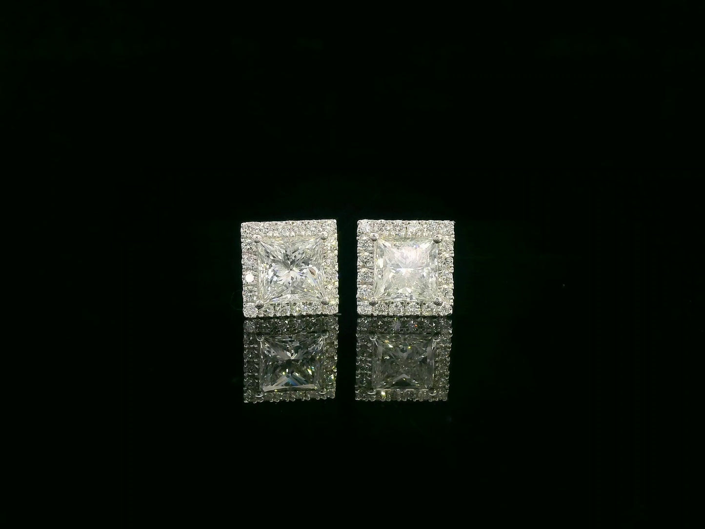 Princess cut diamond halo stud earrings in 18K white gold featuring GIA certified 1.01 carat E color VS2 diamonds with halo accents by Emirates Diamonds