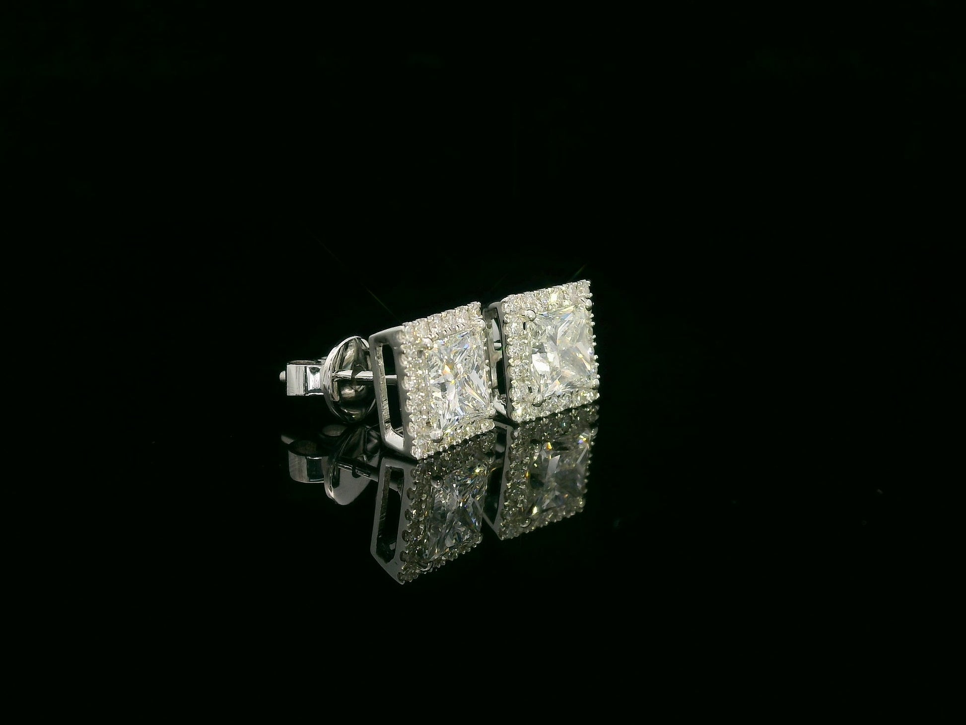 Princess cut diamond halo stud earrings in 18K white gold featuring GIA certified 1.01 carat E color VS2 diamonds with halo accents by Emirates Diamonds