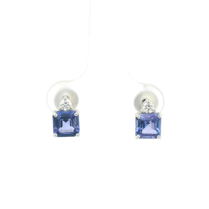 Pair of 18K white gold tanzanite and diamond stud earrings featuring square emerald-cut blue-violet tanzanites with a round diamond accent above each gemstone.