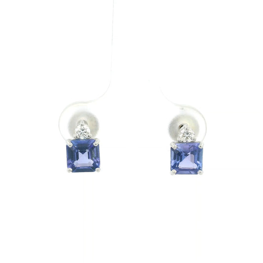 Pair of 18K white gold tanzanite and diamond stud earrings featuring square emerald-cut blue-violet tanzanites with a round diamond accent above each gemstone.