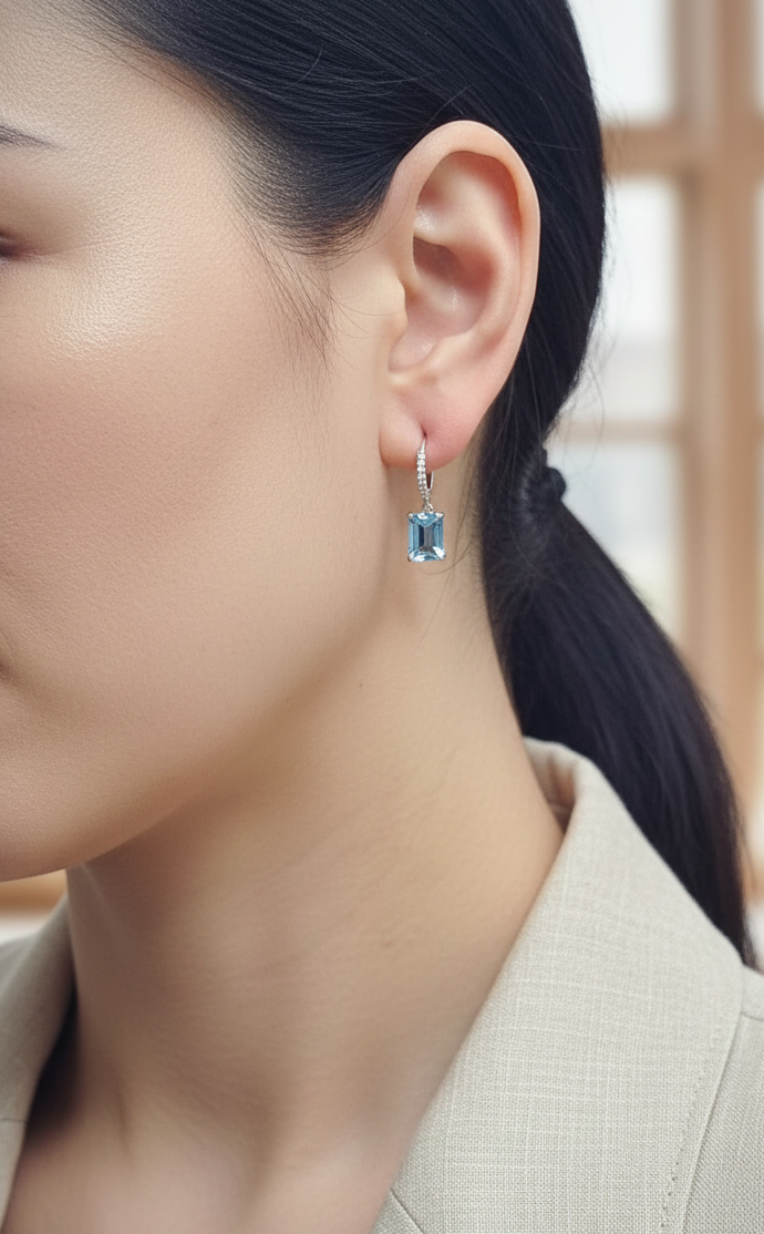 18K white gold hoop drop earrings featuring emerald-cut Swiss Blue Topaz and diamond accents by Emirates Diamonds.