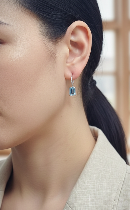 18K white gold hoop drop earrings featuring emerald-cut Swiss Blue Topaz and diamond accents by Emirates Diamonds.