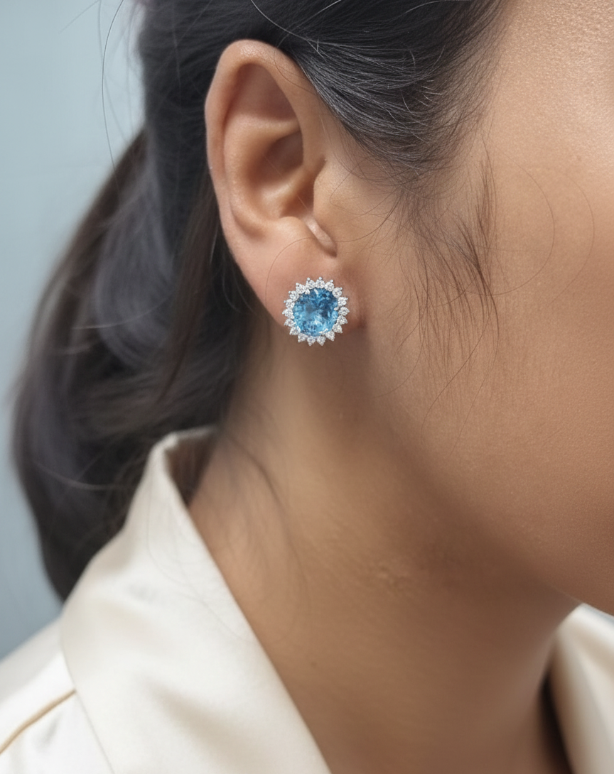 18K white gold stud earrings featuring oval Swiss blue topaz gemstones surrounded by diamond halos