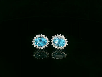 18K white gold stud earrings featuring oval Swiss blue topaz gemstones surrounded by diamond halos
