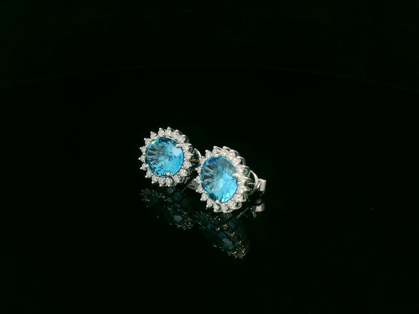 18K white gold stud earrings featuring oval Swiss blue topaz gemstones surrounded by diamond halos