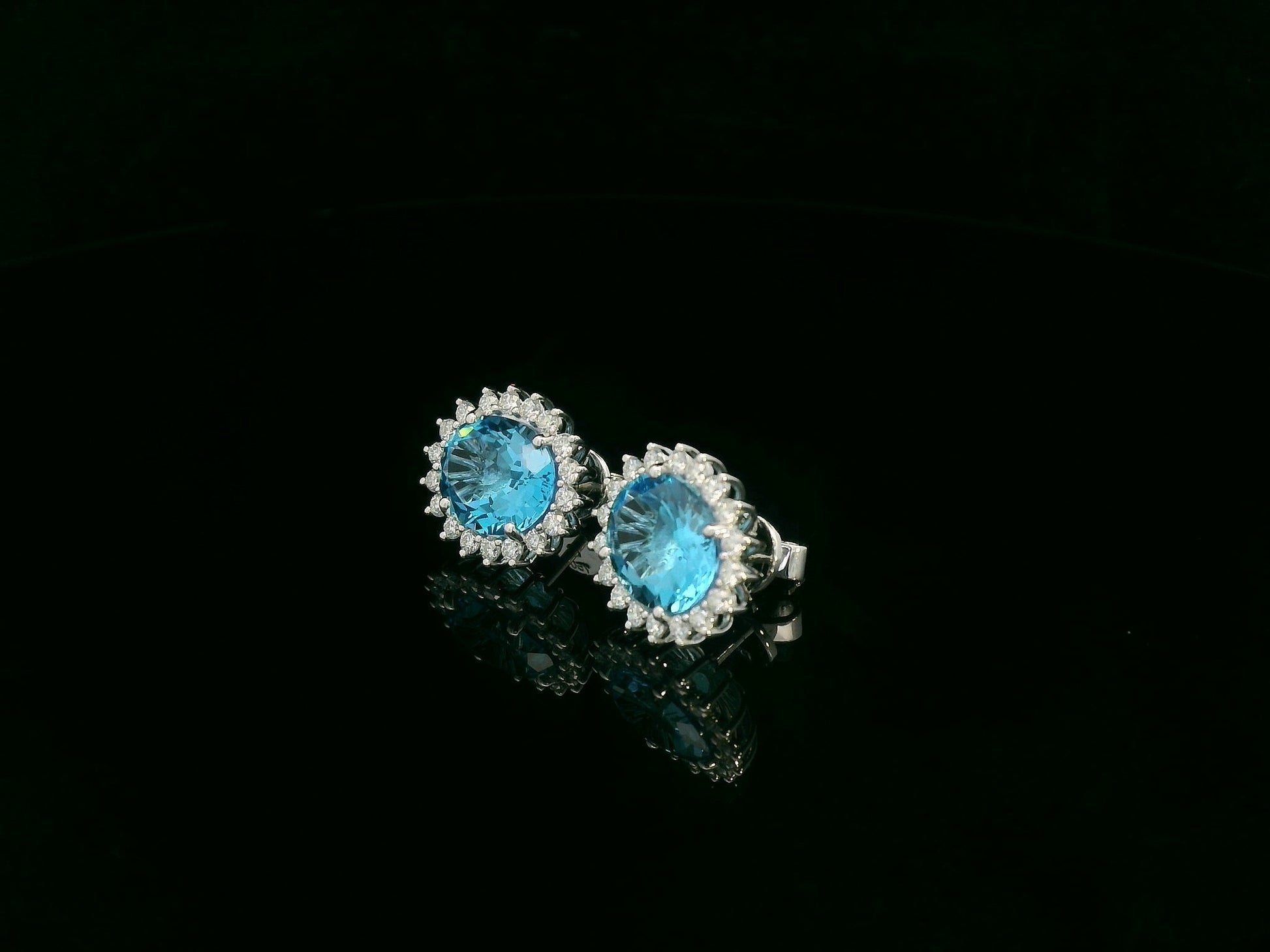 18K white gold stud earrings featuring oval Swiss blue topaz gemstones surrounded by diamond halos
