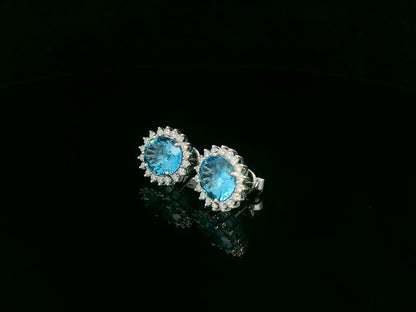 18K white gold stud earrings featuring oval Swiss blue topaz gemstones surrounded by diamond halos