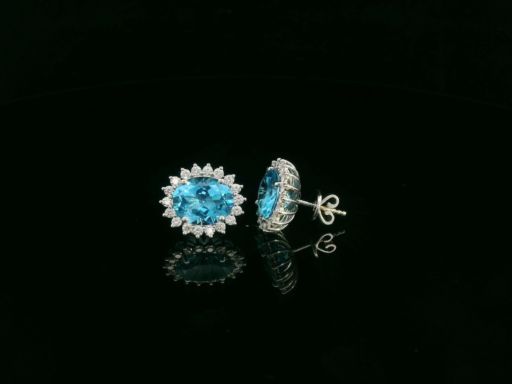 18K white gold stud earrings featuring oval Swiss blue topaz gemstones surrounded by diamond halos