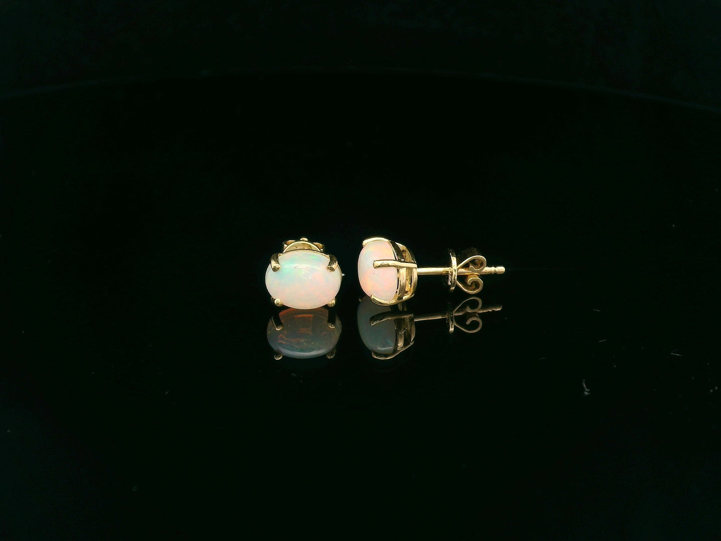 18K yellow gold opal stud earrings featuring 1.63 carat oval opals with classic prong setting by Emirates Diamonds.