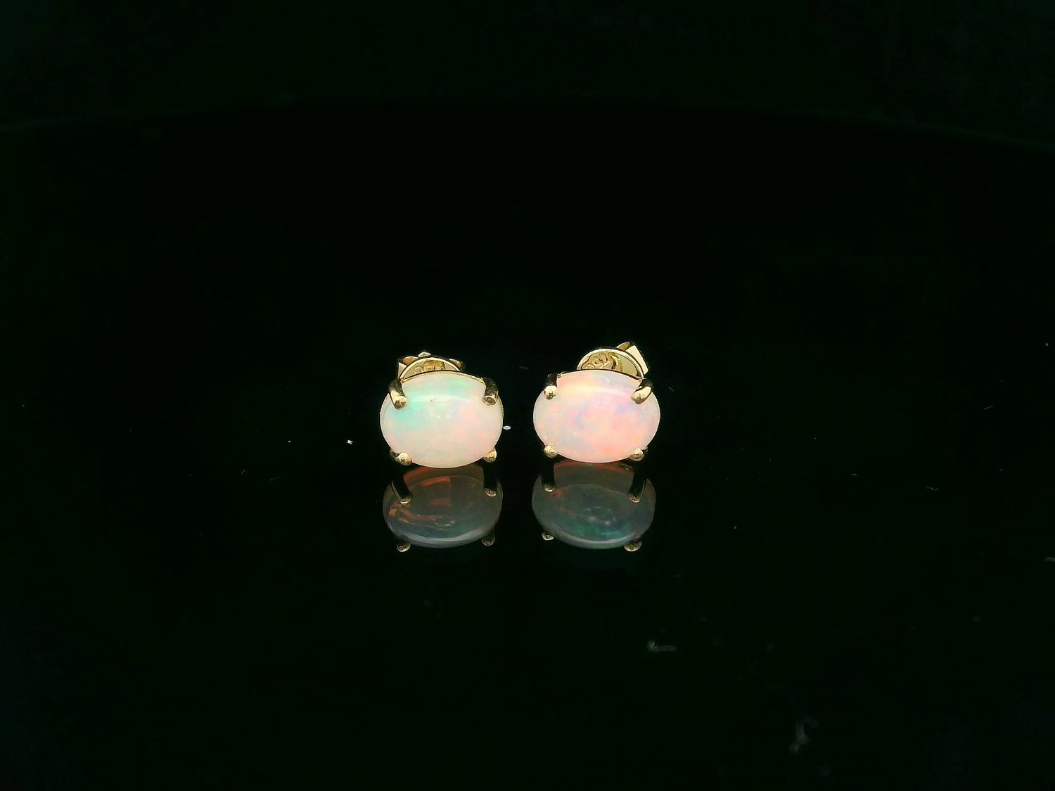 18K yellow gold opal stud earrings featuring 1.63 carat oval opals with classic prong setting by Emirates Diamonds.