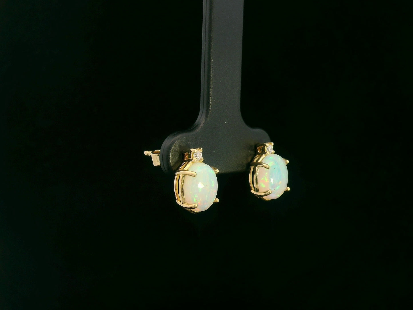18K yellow gold opal and diamond stud earrings with oval opals and subtle diamond accents, luxury fine jewelry by Emirates Diamonds.
