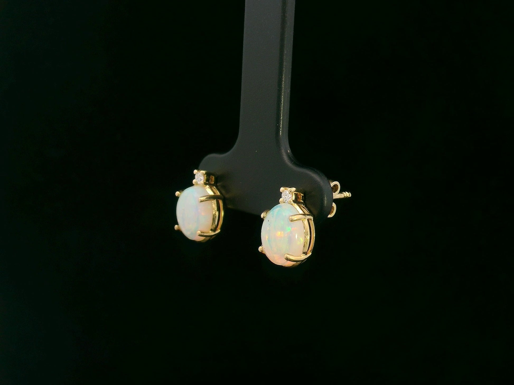 18K yellow gold opal and diamond stud earrings with oval opals and subtle diamond accents, luxury fine jewelry by Emirates Diamonds.